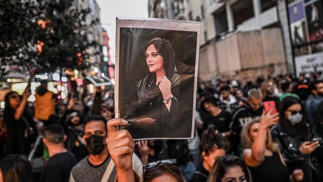 A protester holds a portrait of Mahsa Amini  during a demonstration in support of Amini, a young Iranian woman who died after being arrested in Tehran by the Islamic Republic's morality police, on Istiklal avenue in Istanbul on September 20, 2022. - Amini, 22, was on a visit with her family to the Iranian capital when she was detained on September 13 by the police unit responsible for enforcing Iran's strict dress code for women, including the wearing of the headscarf in public. She was declared dead on September 16 by state television after having spent three days in a coma. (Photo by Ozan KOSE / AFP)