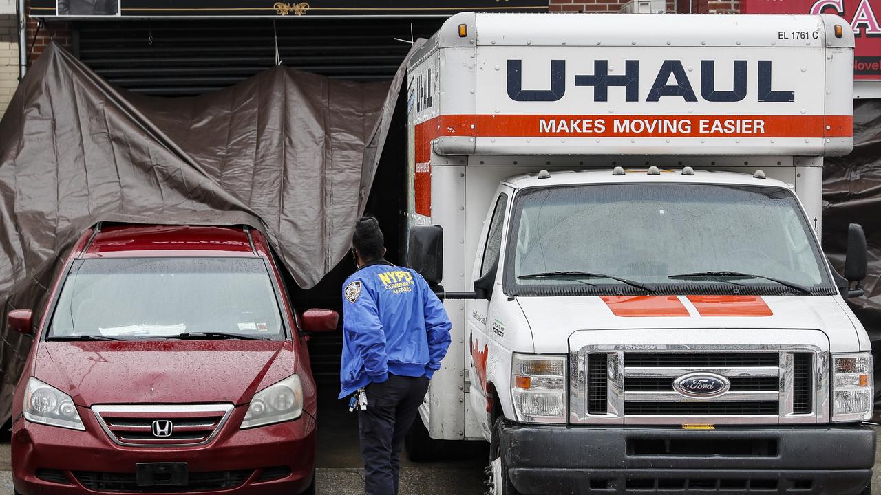 A NYPD officer walks up beside rental trucks and a hearse partially covered by a tarp outside Andrew T. Cleckley Funeral Home, Thursday, April 30, 2020, in the Brooklyn borough of New York. Picture: AP /John Minchillo.