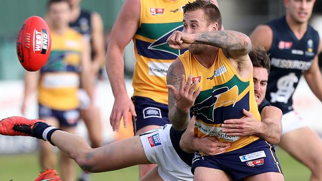 Woodville-West Torrens’ Scott Lewis gets his handball away, ahead of a strong tackle by South Adelaide’s Nic Schwarz. Picture: Calum Robertson