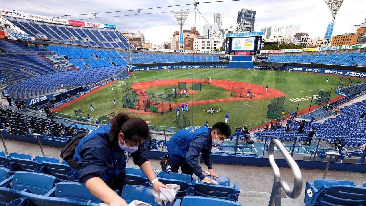 Workers take cleaning seats of the Yokohama Stadium, which will host baseball and softball games during the Tokyo Olympics, prior to a professional baseball game in Yokohama. Photo: Kazuhiro NOGI / AFP