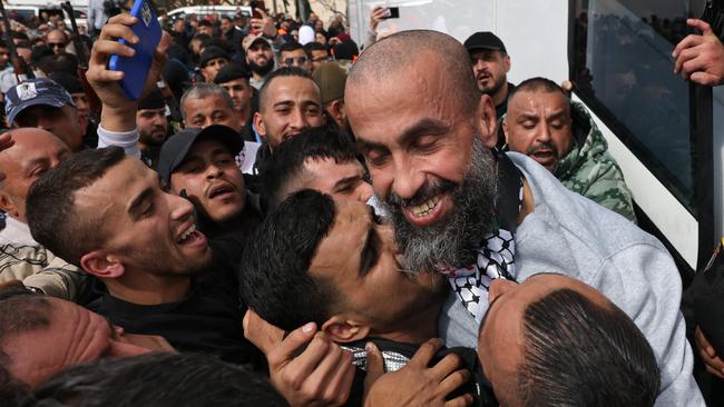 A former Palestinian prisoner released by Israel is hugged by members of his family as he disembarks a Red Cross bus after arriving in Ramallah, in the occupied West Bank on Saturday. Picture: AFP