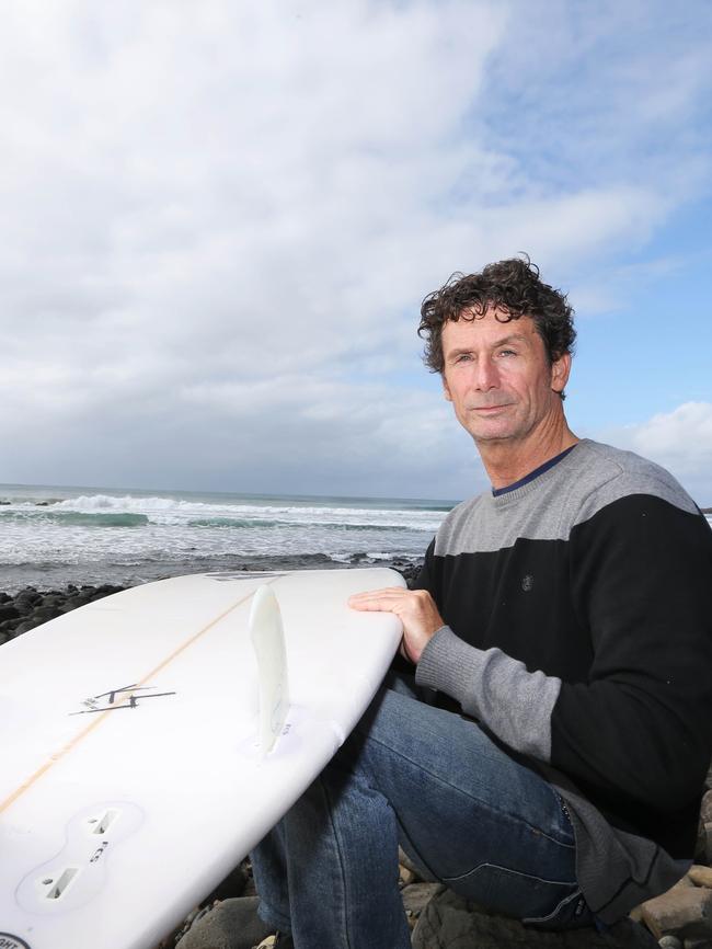 Surfer Mick Hoile inspects the teeth marks on his board after being attacked by a shark. Picture: Jason O'Brien