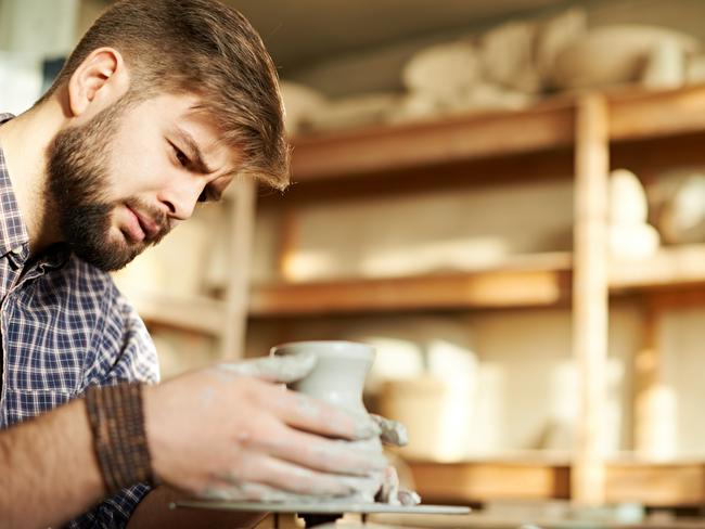 Young bearded man working at pottery studio