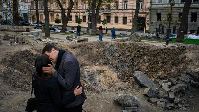 A couple kiss by a rocket crater in a park of central Kyiv. Picture: AFP