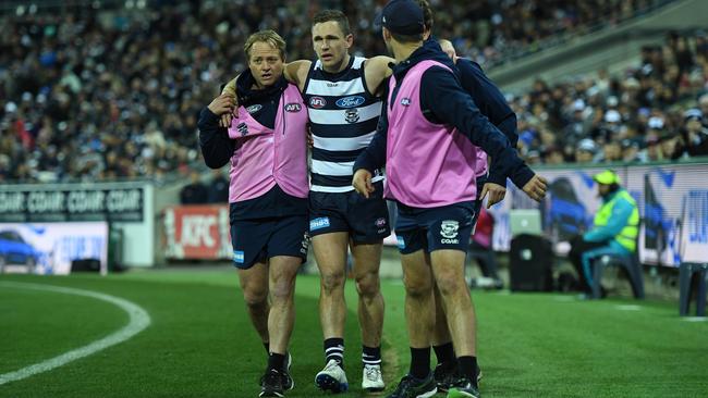 Joel Selwood is helped from the field after injuring his ankle.