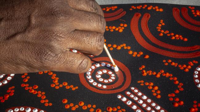 Dot painting with a local Aboriginal artist in the Uluru-Kata Tjuta National Park cultural centre. CLC CEO Joe Martin-Jard has welcomed the recommendation in the TERC report to have more tourists visit the Territory to experience its Aboriginal culture. Picture: Tourism NT/Archie Sartracom