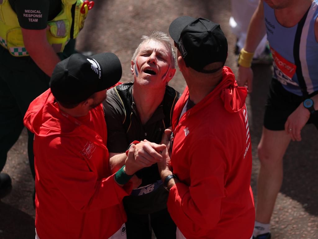 An exhausted runner is assisted at the finish line. / AFP PHOTO / Daniel LEAL-OLIVAS