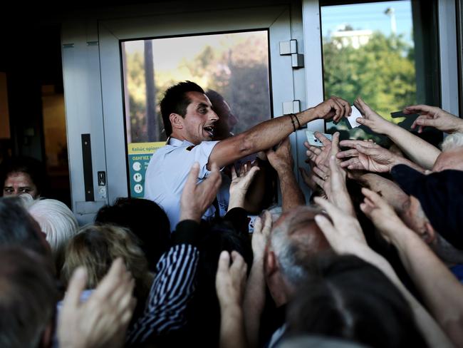 Desperate times ... The manager of a national Bank branch delivers priority numbers to pensioners. Picture: AFP/ANGELOS TZORTZINIS