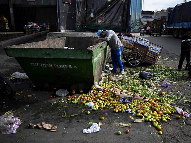 A man searches food inside a trash can where discarded fruits and vegetables are deposited at the Central Market in Buenos Aires, on May 12, 2023.