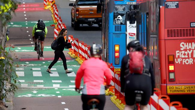 Buses now have to stop in the middle lane to let people on or off and commuters have to watch for cyclists as they walk across the bike lane. Picture: Toby Zerna