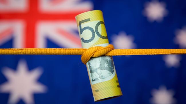 Studio shot close up of an Australian dollar note tied in a knot with the Australian flag as a background. Mortgage home loan money stress generic