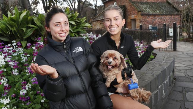 Lexie McIntyre, Olivia O’Connor and dog Monty outside Cooks Cottage in Fitzroy Gardens. Picture David Crosling