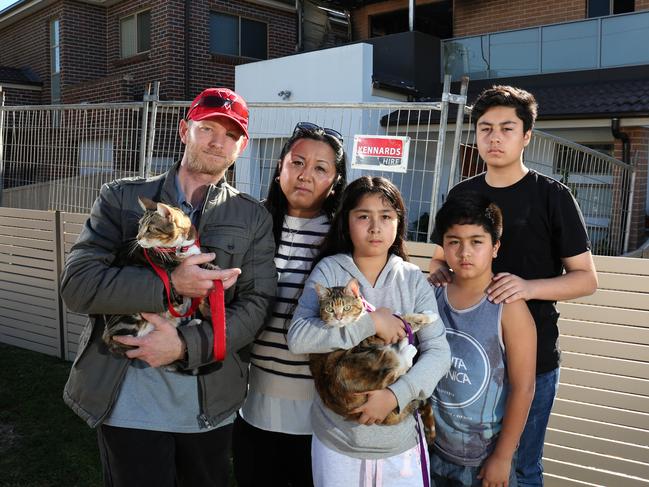 Chris Dunlop, Nerissa Long, Ariyanna (12), Nathaniel (11), Charles (15) and their cats. Tails and Assami. in front of their old home. Picture: Robert Pozo