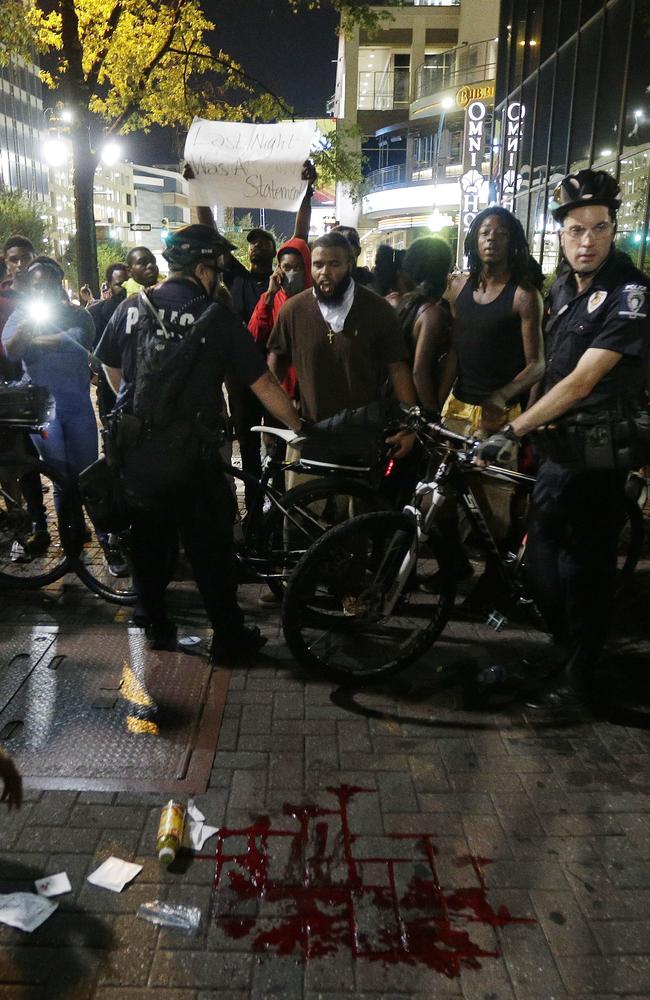 Police circle an area where a pool of blood lies after a man was injured during a protest. Picture: AP/Chuck Burton