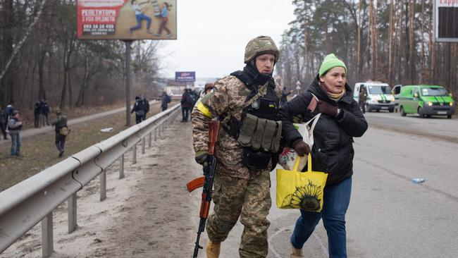 A Ukrainian servicemen helps a woman during the evacuation of civilians in Irpin on Sunday. Picture: Getty Images