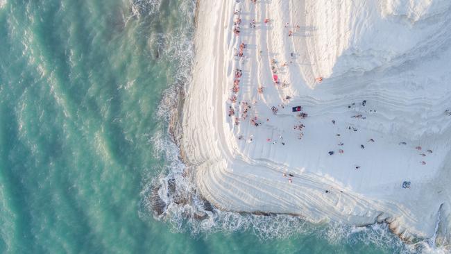 Image Name: The Big MeringuePhotographer Name: Placido  FarandaYear: 2018Image Description: Scala dei Turchi (The Turkish Steps) is a white cliff in Realmonte (Sicily), made of a soft limestone and a blinding white marl. Natural erosion has created steps on the cliff face, making it look soft and sinuous, like a Big Meringue covered with sprinkles (the people sitting and walking on it). The origin of the name “Turkish Steps” is intriguing. While there is a big resemblance to Pamukkale (Turkey), the designation of “Turkish” was given centuries ago by local people, for the frequent raids carried by Turkish pirates on this area. Legend says they would find a shelter for their boats behind this rocky formation, and then climb the “steps” of the cliff and raid the villages. Today, Scala dei Turchi is a wonderful spot for viewing the sunset, as the bright white marl turns into a strong orange. Only after shooting this image, while watching it on a bigger screen, I noticed a newlywed couple in the frame kissing for their wedding photoshoot. Exactly at the edge of the cliff.Copyright: Placido  Faranda, Italy, Entry, Open, Landscape & Nature (2018 Open competition), 2018 Sony World Photography Awards