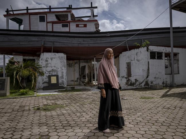 A tsunami survivor, Bundiyah, stands in front of a boat washed up onto a house in Banda Aceh. Picture: Getty Images