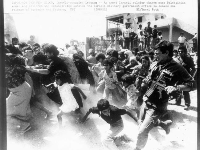 An armed Israeli soldier chases away Palestinians in Lebanon, 1982. Picture: UPI. (ISRAEL) HL/Yossi Roth.