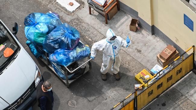 A worker wearing personal protective equipment (PPE) pulling a cart with bags stands at a checkpoint during a Covid-19 coronavirus lockdown in the Jing'an district in Shanghai. Picture: Hector Retamal/AFP