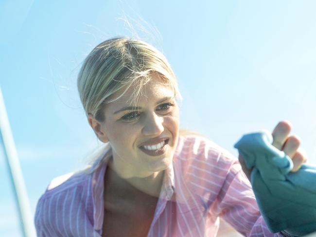 Blonde girl in pink shirt polishing the windshield paying attention to every little detail, washing car generic