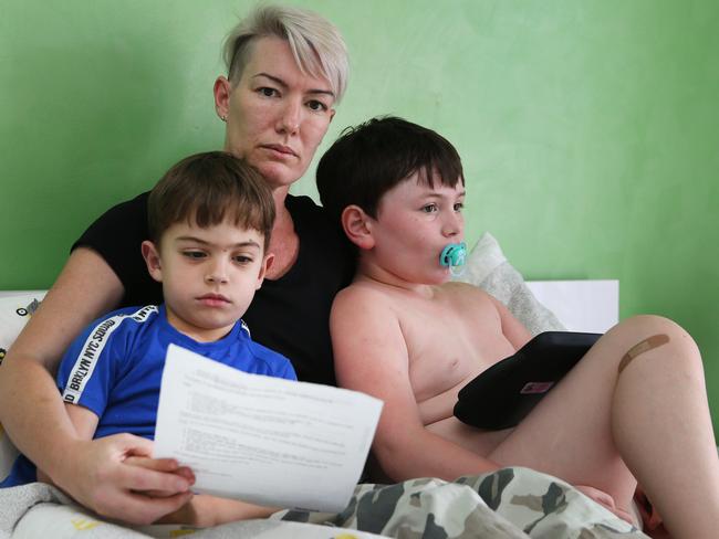 Shannon Manning reads a letter from the NDIS with her children Madden six. and Meadow, seven. Ms Manning is still looking for assistance to get a wheelchair for her severely disabled daughter. Picture: Glenn Hampson