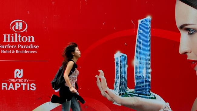 A tourist passes a former Raptis project, the Gold Coast Hilton, which was put into receivership.