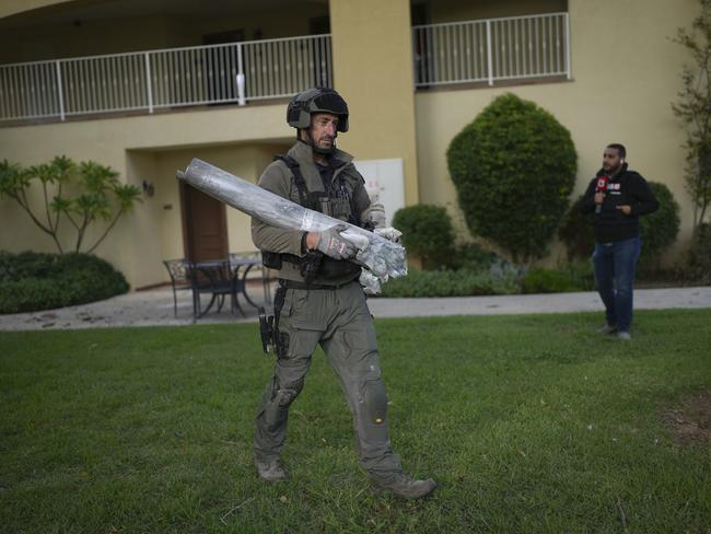 An Israeli bomb squad policeman carries the remains of a rocket that was fired from Lebanon in Kibbutz Kfar Blum, northern Israel. Picture: AP