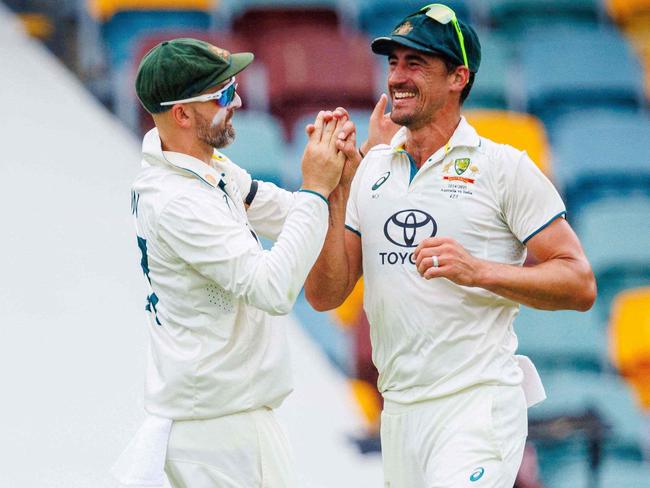 Australia's Marnus Labuschagne (L), Nathan Lyon (C) and Mitchell Starc celebrate the wicket of India's Virat Kohli on day three of the third Test match between Australia and India at The Gabba in Brisbane on December 16, 2024. (Photo by Patrick HAMILTON / AFP) / -- IMAGE RESTRICTED TO EDITORIAL USE - STRICTLY NO COMMERCIAL USE --