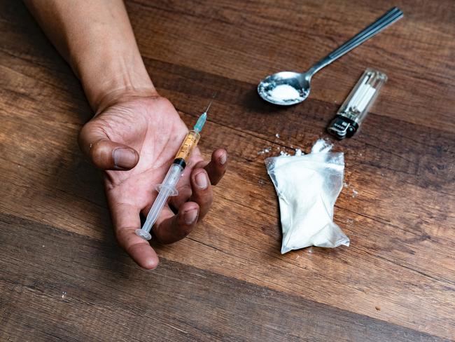 Human hand of a drug addict and a syringe with narcotic syringe lying on the floor. Anti drug concept.