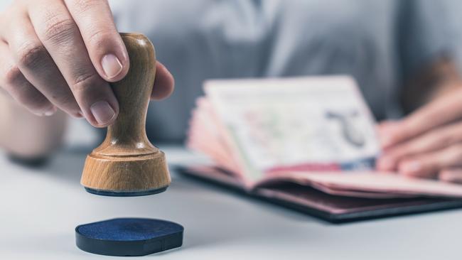 Immigration and passport control at the airport. woman border control officer puts a stamp in the US passport of american citizen. ConceptEscape 18 February 2024Why I TravelPhoto - iStock