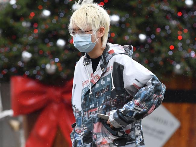 A woman wearing a protective face covering to combat the spread of the coronavirus, walks past a solitary Christmas Tree in a near-deserted Covent Garden in central London on November 19, 2020, as life under a second lockdown continues in England. - The current lockdown in England has shuttered restaurants, gyms and non-essential shops and services until December 2, with hopes business could resume in time for Christmas. (Photo by JUSTIN TALLIS / AFP)