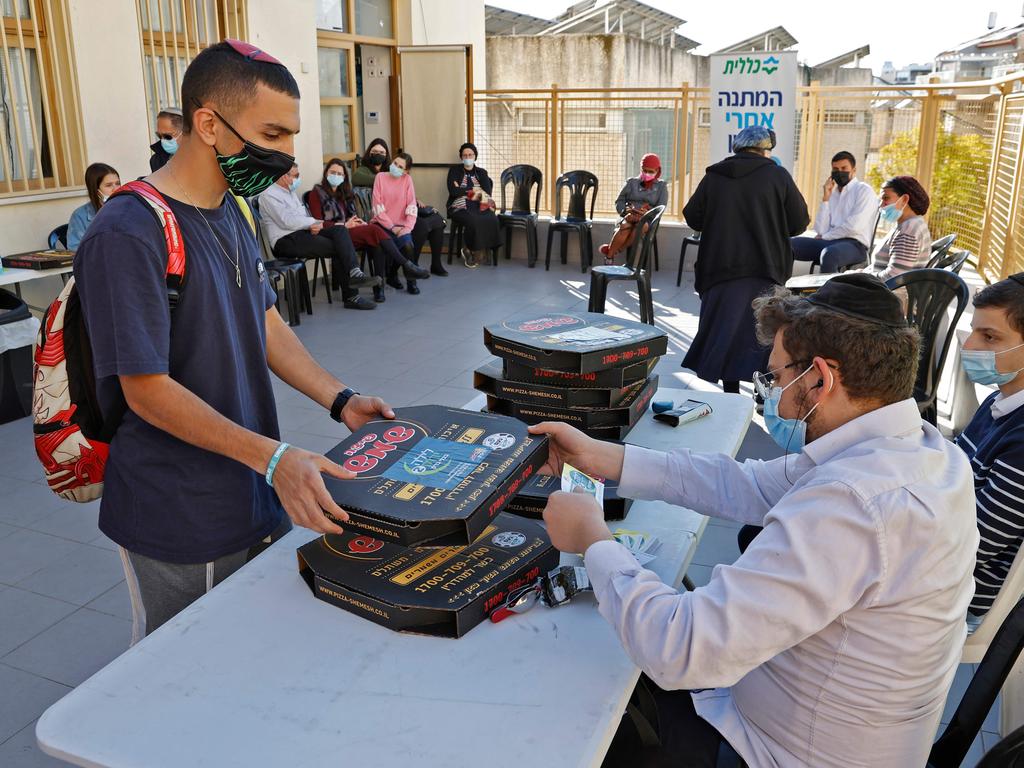 People receive pizza after getting the Pfizer vaccine in the Israeli city of Bnei Brak. Picture: Jack Guez/AFP