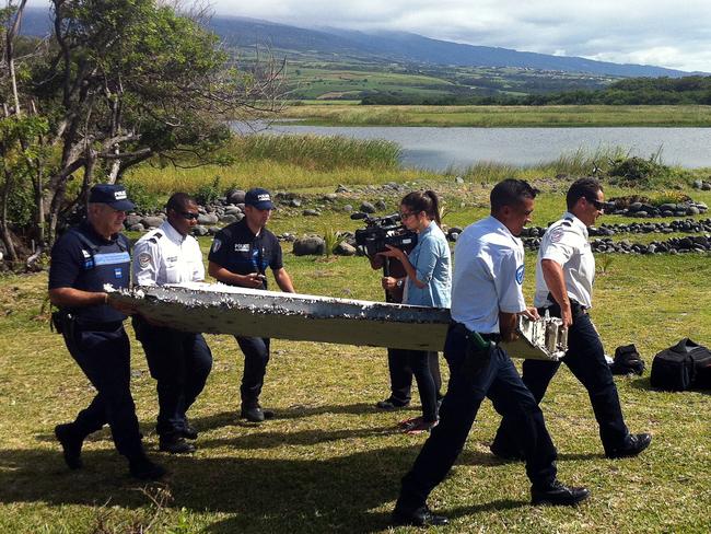 Debris ... French police carry a piece of debris from a plane found in the coastal area of Saint-Andre de la Reunion, in the east of the French Indian Ocean island of La Reunion. Malaysian authorities have since said it was from MH370. Picture: AFP/ Yannick Pitou