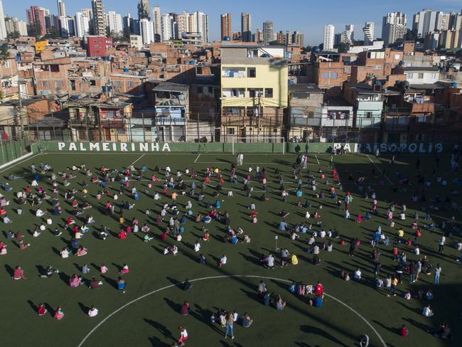 Residents of a slum in Sao Paolo, Brazil, gather on a soccer field to receive kits equipped with cleaning products and protective face masks for children. Picture: AP.