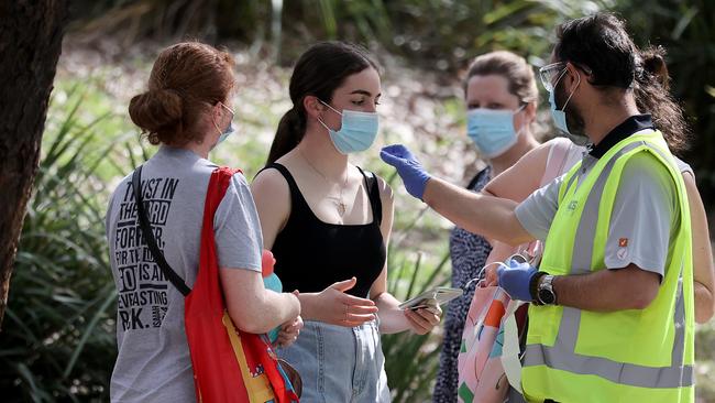 A man puts a sticker on a woman’s shoulder after she shows her phone check in and Medicare card at he Homebush Vaccination centre. Picture: NCA NewsWire / Dylan Coker