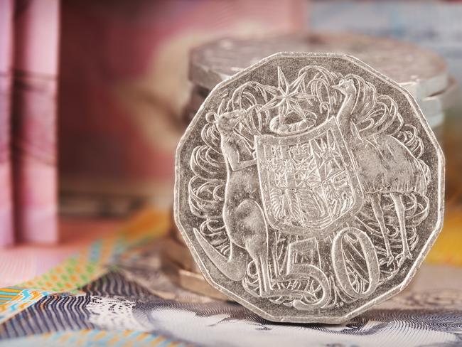 Australian Fifty Cent Coin. Note this is a circulated coin so has some nicks and scratches. Stock image of a pile of Australian 50 cent coins with Australian money in background.