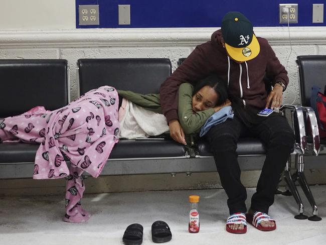 Latreece Smith rests as her friend Tamari Cameron checks flight information at the Fort Lauderdale-Hollywood International Airport following the cancellation of multiple Spirit Airlines flights. Picture: Joe Cavaretta/South Florida Sun-Sentinel via AP
