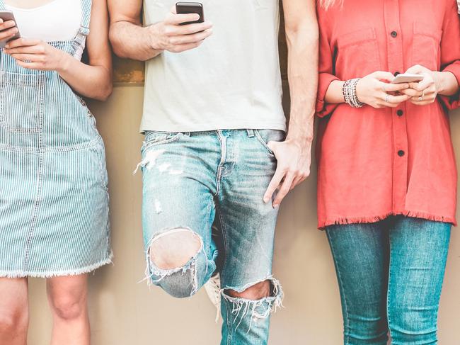 Group of millennial friends watching smart mobile phones - Teenagers addiction to new technology trends - Concept of youth, tech, social and friendship - Focus on smartphones