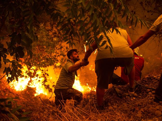 TOPSHOT - Local residents fight the wildfire in the village of Gouves on Evia (Euboea) island, second largest Greek island, on August 8, 2021. - Hundreds of Greek firefighters fought desperately on August 8 to control wildfires on the island of Evia that have charred vast areas of pine forest, destroyed homes and forced tourists and locals to flee. (Photo by ANGELOS TZORTZINIS / AFP)