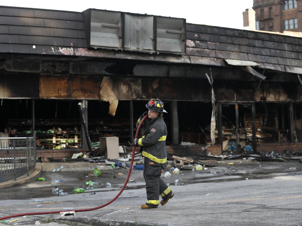 A member of the St. Louis Fire Department removes a hose outside a vandalised and burned convenience store in St. Louis. Picture: Jeff Roberson