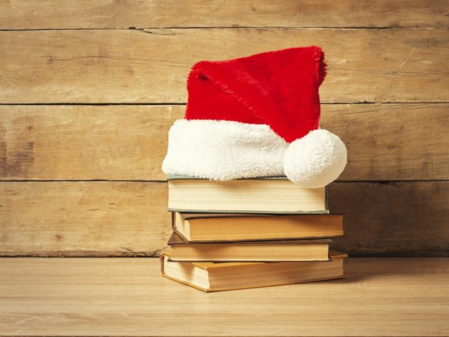 Stack of books, Santa's hat on a wooden background. Holiday concept, christmas, christmas eve.