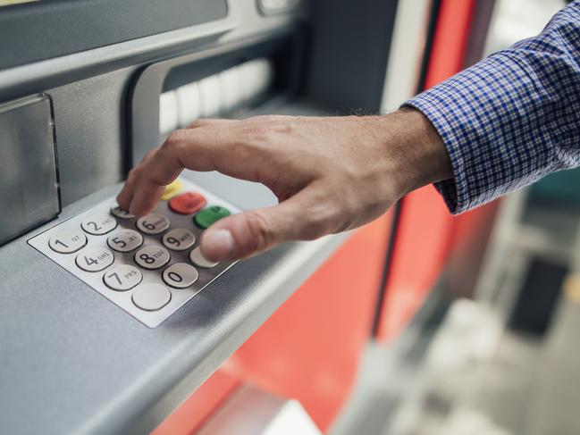 Close up shot of a businessman's hand pressing keys on a cash machine to get money out.