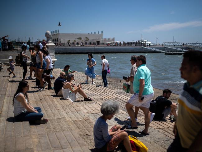 People look at the Tagus river as they sit at the quay in Lisbon. Picture: AFP