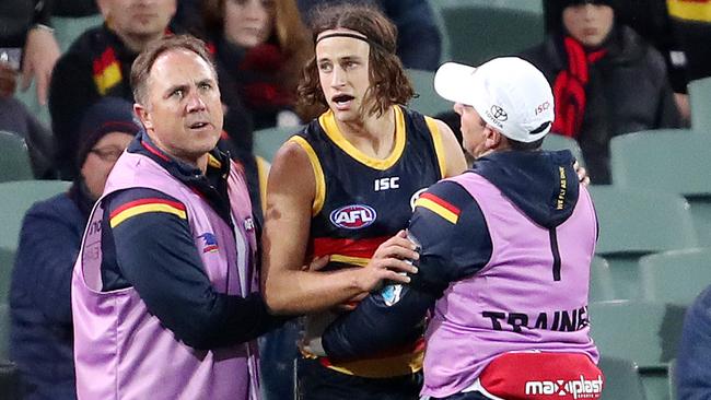 Will Hamill is helped off the ground by trainers after being dumped in a tackle.