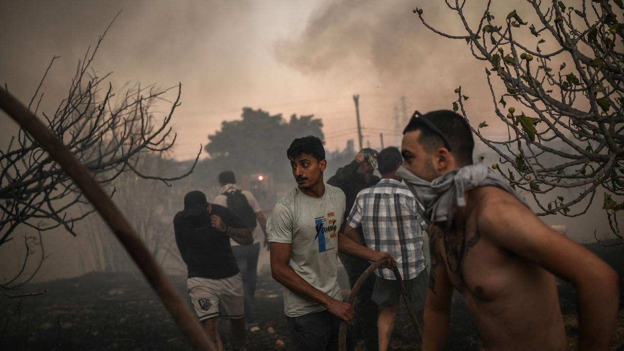 Locals try to extinguish a wildfire. Greece's civil protection authorities ordered the evacuation of several towns in the north-eastern suburbs of Athens. (Photo by Angelos TZORTZINIS / AFP)