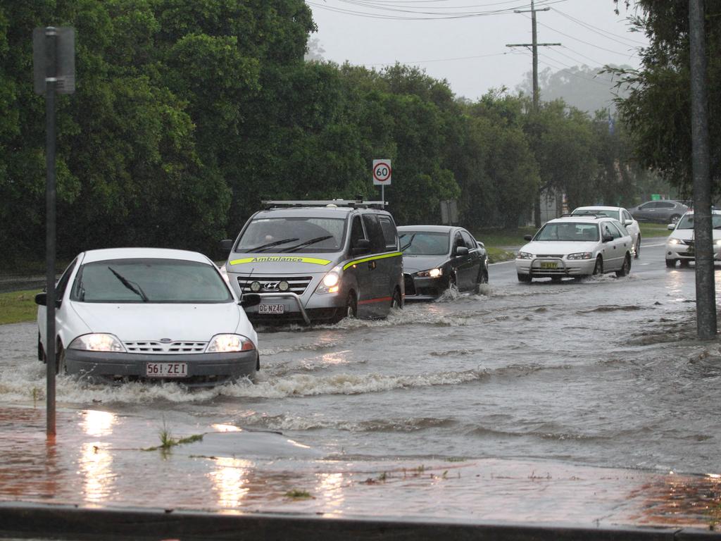 Vehicles slowly make their way through floodwaters during a heavy downpour on the southern end of the Gold Coast. Picture: Mike Batterham