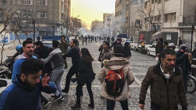 People are affected by tear gas fired by anti-riot Iranian police to disperse demonstrators in Tehran, Iran on Saturday. (Pic: AP Photo)