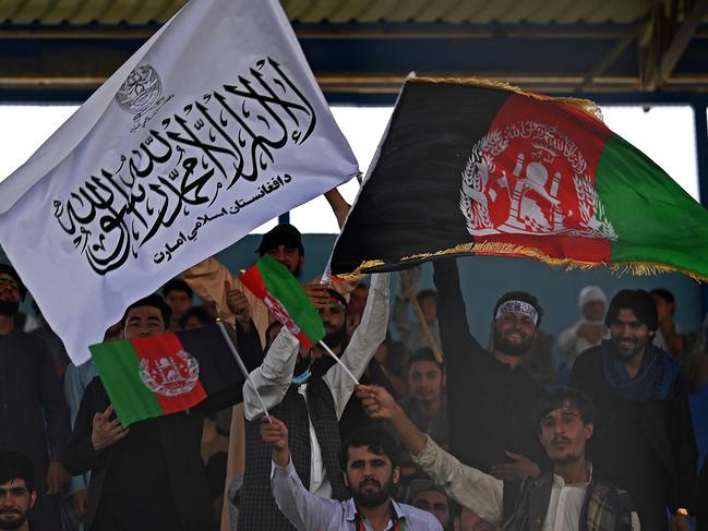 Spectators wave Afghanistan's and Taliban flags as they watch the Twenty20 cricket trial match being played between two Afghan teams 'Peace Defenders' and 'Peace Heroes' at the Kabul International Cricket Stadium in Kabul on September 3, 2021. (Photo by Aamir QURESHI / AFP)