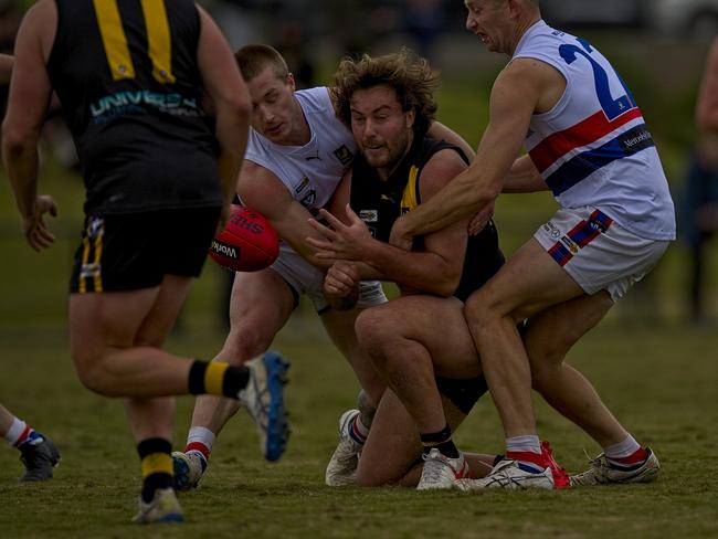 Seaford’s Tim Broomhead gets the ball away despite being tackled by two Mornington players.