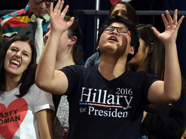 People sing as they watch elections returns during election night at the Jacob K. Javits Convention Center in New York on November 8, 2016. US Democratic presidential nominee Hillary Clinton will hold her election night event at the convention center. / AFP PHOTO / Don EMMERT